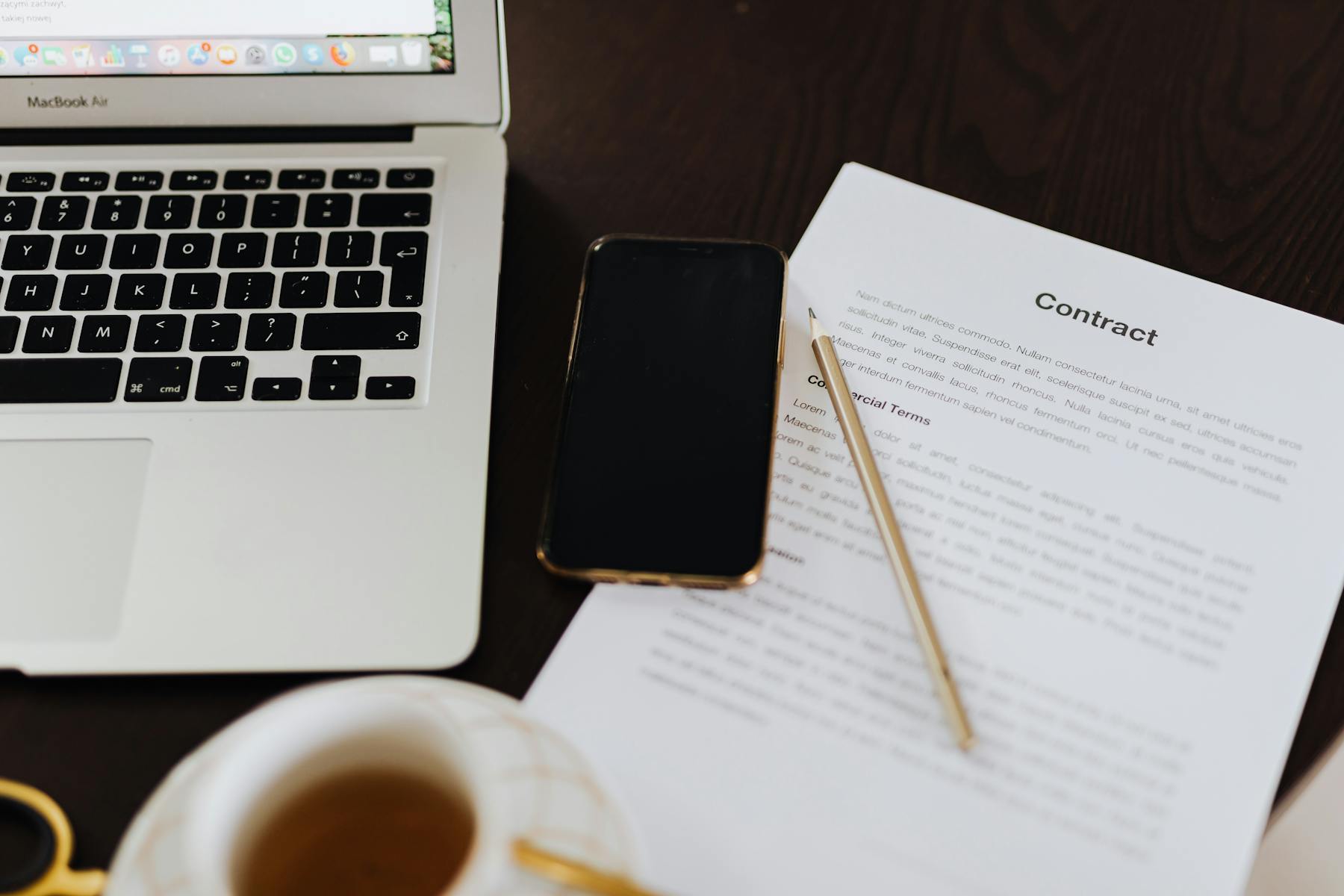 Laptop, smartphone en contractdocumenten op een bureau